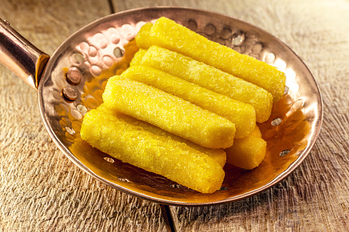 Fried polenta in a slotted spoon, typical Brazilian food, cornmeal and cornmeal snacks