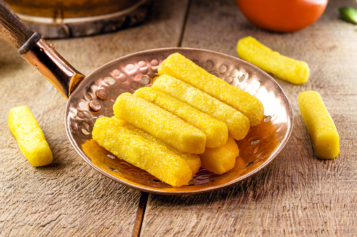 Fried polenta in a slotted spoon, typical Brazilian food, cornmeal and cornmeal snacks