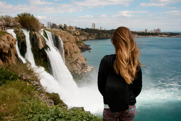 rear view of beautiful woman on background of Duden waterfall in Antalya,Turkey. rear view of beautiful woman with long hair on the background of Duden waterfall in Antalya. Famous places of Turkey. Duden stock pictures, royalty-free photos & images