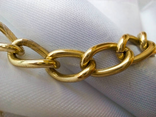 gold metal chain on white cloth
