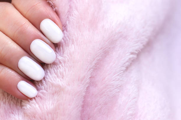 istock Hand with white nails on pink textile background 1323883185