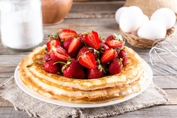 istock Plate of delicious thin pancakes with berries on table 1323883412