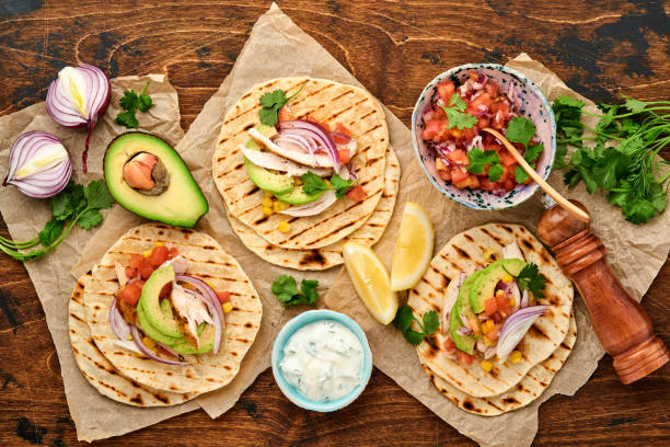 istock Mexican tacos with grilled chicken, avocado, corn kernels, tomato, onion, cilantro and salsa old wooden table. Traditional Mexican and Latin american street food. Top view. 1323884526