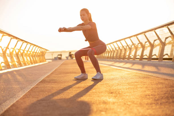 istock Athletic red head woman doing squats with an expander 1323884785