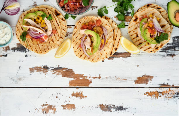 istock Mexican tacos with grilled chicken, avocado, corn kernels, tomato, onion, cilantro and salsa old white wooden table. Traditional Mexican and Latin american street food. Top view. 1323884826