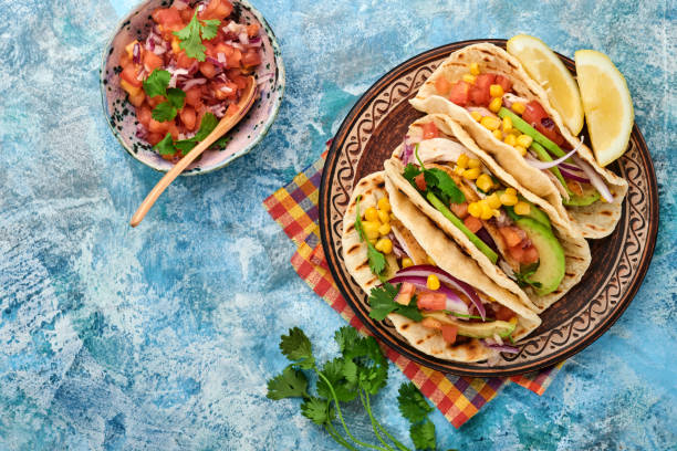 istock Mexican tacos with grilled chicken, avocado, corn kernels, tomato, onion, cilantro and salsa at blue stone table. Traditional Mexican and Latin american street food. Top view. 1323884992