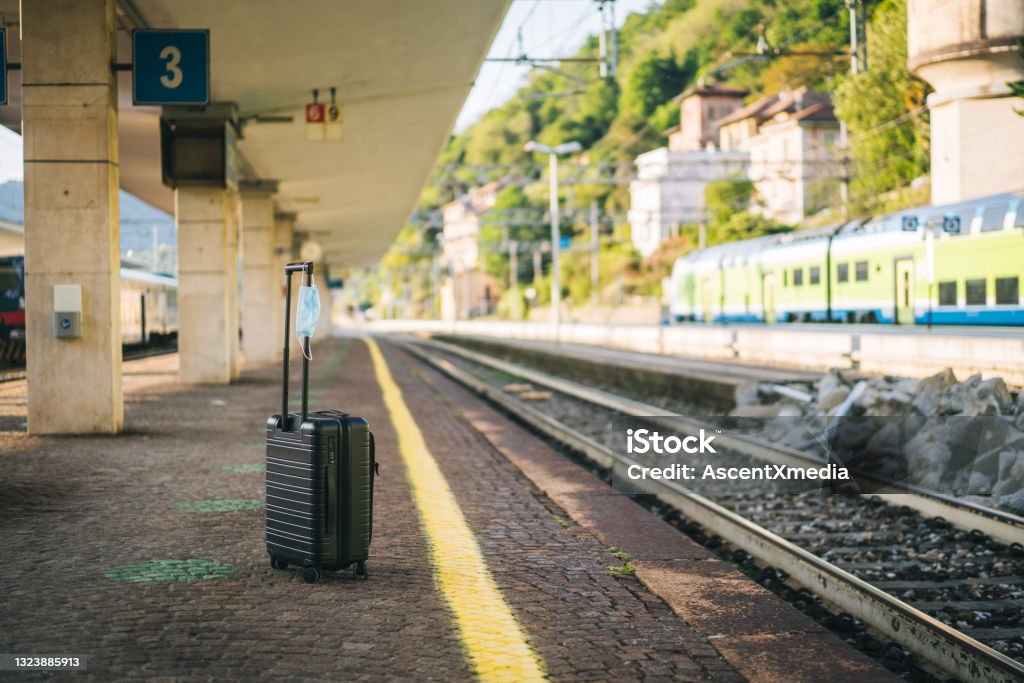 Scenic view of suitcase sitting at platform of train station Suitcase with a protective face mask to protect from covid-19 infection, Suitcase Stock Photo