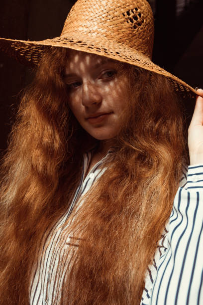 istock Lovely young red haired model with long wavy hair in straw hat 1323886156