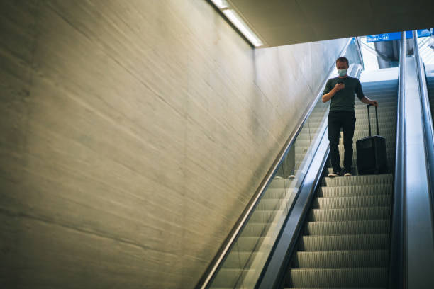 istock Young man texts friend from escalator in train station 1323886408