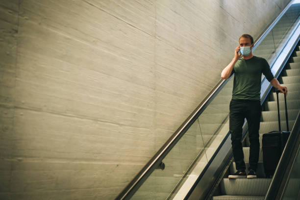 istock Young man calls friend from escalator in train station 1323886477