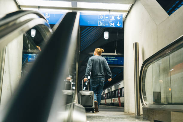 istock Young man walks through train station, towards his platform 1323887114