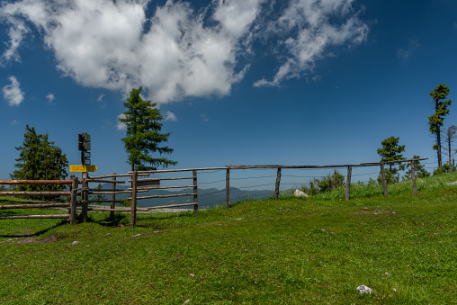 Pass near Niederer Schockl hill with green meadows and fences in Austria