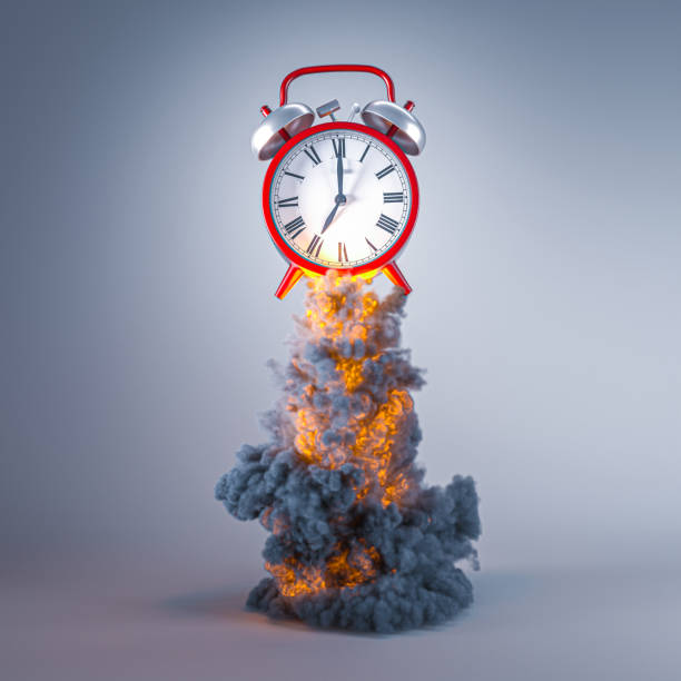 istock classic red alarm clock with flames and smoke. 1323888942