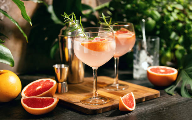 Pink grapefruit and rosemary gin cocktail is served in a prepared gin glasses Pink grapefruit and rosemary gin cocktail  served in prepared gin cocktail glass on a tropical beach bar bar area stock pictures, royalty-free photos & images