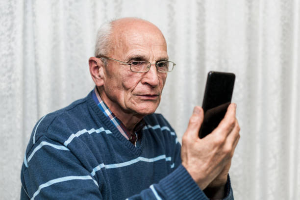 istock Serious senior man wearing glasses using smartphone and looking at camera 1323895534