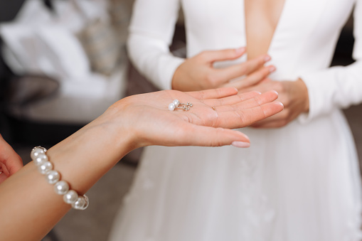 Wedding earrings on a female hand wear, she takes the earrings, the bride fees, morning bride, woman in white dress.
