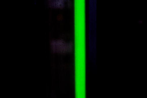 A bright green fluorescent, neon light in a dark store window.