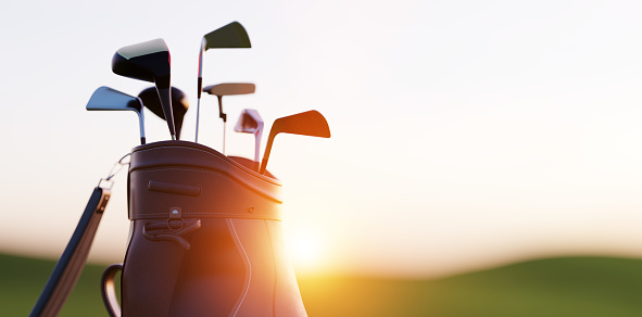 Golf clubs in bag at golf course resort at sunset