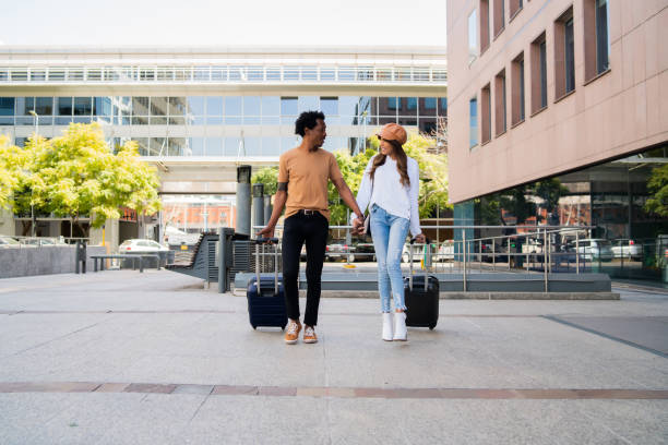 istock Tourist couple carrying suitcase while walking outdoors. 1323901976