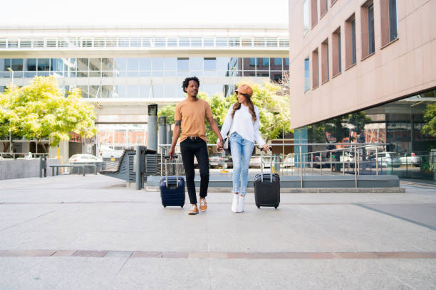 istock Tourist couple carrying suitcase while walking outdoors. 1323901977