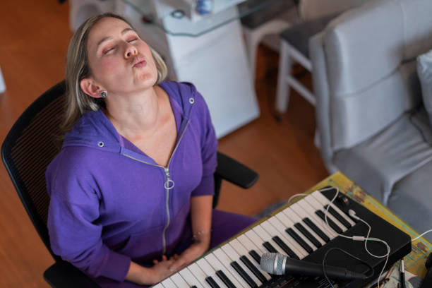 The Latin singing teacher from Bogotá Colombia, between 30 and 39 years old, performs mouth and tongue exercises while giving her virtual singing classes using her pajamas from home