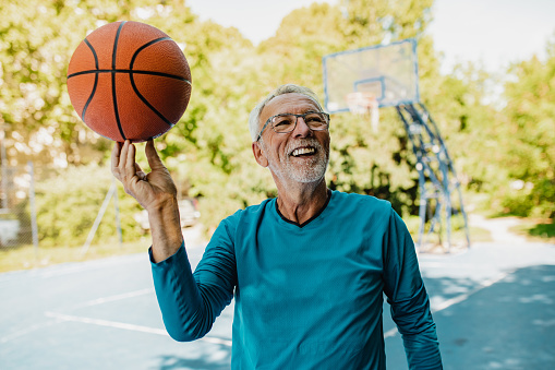 Photo of a senior man on the basketball field holding a ball and walking