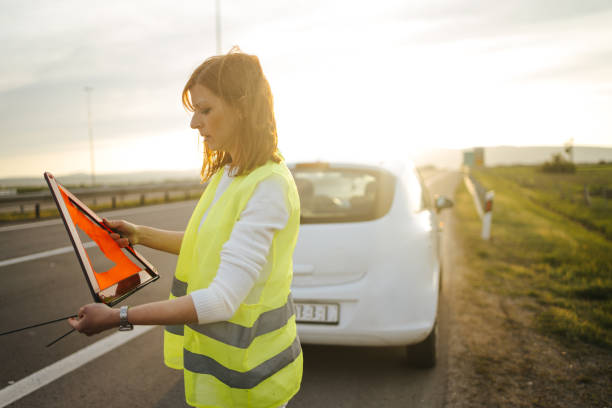 istock Woman setting up a warning triangle after her car broke down. Car breakdown on the highway 1323904227