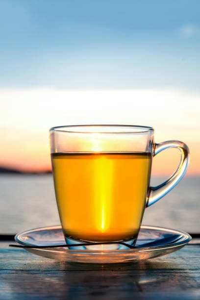 tazza di tè verde davanti alla luce del tramonto sul tavolo di legno. - tea island foto e immagini stock