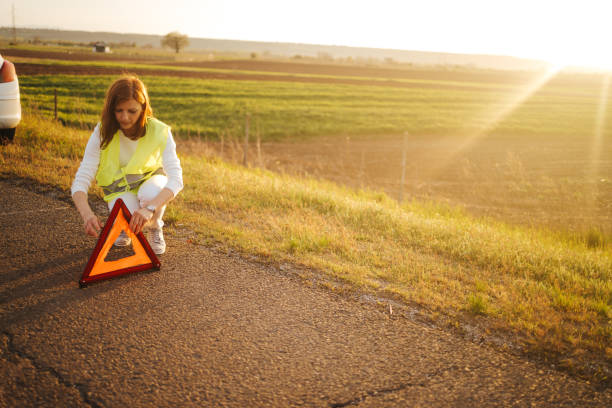 donna che ha insaiato un triangolo di avvertimento dopo che la sua auto si è rotta. guasto auto in autostrada - roadside emergency foto e immagini stock