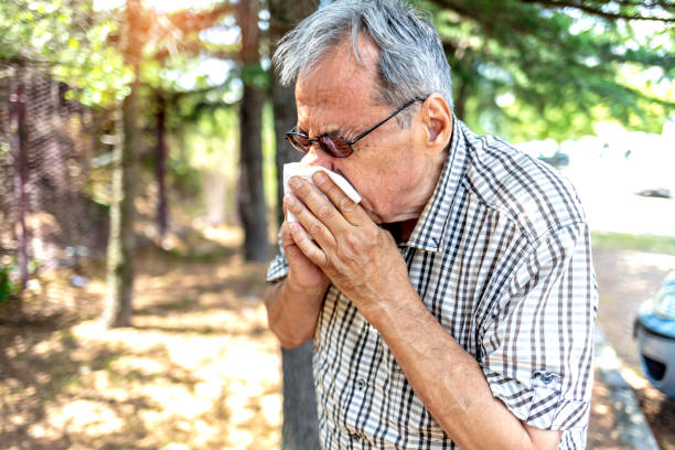istock Sick elderly man with allergy symptoms walking in nature and using paper tissues feeling desperate. 1323905690