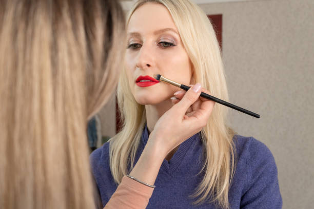 istock Lip make up. Make-up artist manually corrects red lip makeup, finishing touches 1323907346