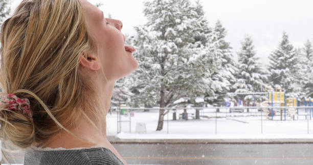 istock Young woman catches fresh falling snow on her face 1323908726