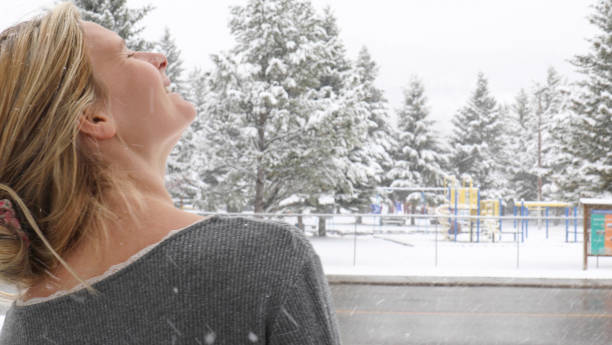 istock Young woman catches fresh falling snow on her face 1323908737