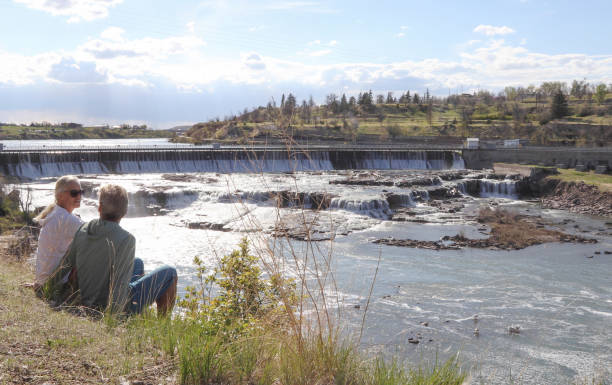 Mature couple watch look down river flowing from dam
