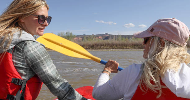 istock Two women kayaking down river pause to chat 1323909358
