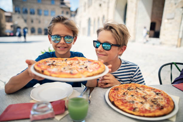 ragazzini che si godono la pizza in un ristorante italiano - piazza delle vettovaglie foto e immagini stock