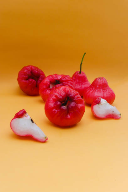 Freshly rose apple fruit isolated on orange background. Also known as jambu air Merah (Syzygium aqueum), jambu Semarang (Syzygium samarangense), Jambu Bol, or Malay Apple (Syzygium malaccense)