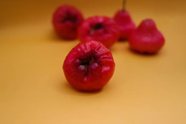 istock Freshly rose apple fruit isolated on orange background. Also known as jambu air Merah (Syzygium aqueum), jambu Semarang (Syzygium samarangense), Jambu Bol, or Malay Apple (Syzygium malaccense) 1323914893