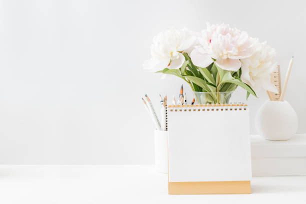 istock Mockup desk calendar and white peonies in a vase on a light background 1323916984