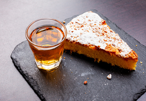 Delicious almond cake Tarta de Santiago served on slate plate with glass of sweet cherry, typical dish of spanish cuisine