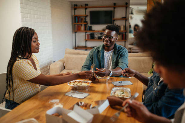 istock Young happy friends having fun during lunchtime at home 1323919094