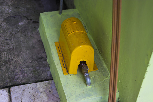 yellow water pump next to the wall as a water reserve at home