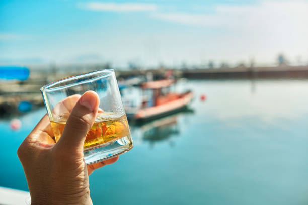 mano masculina sosteniendo whisky de cristal el comienzo del verano en el puerto deportivo, concepto de verano - beginning of life fotografías e imágenes de stock