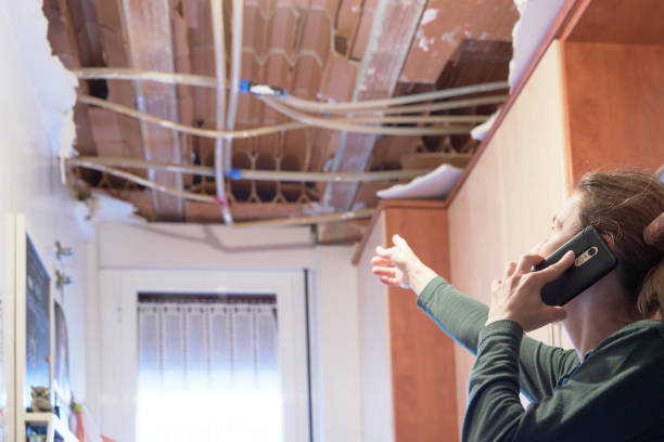 Woman explaining a kitchen ceiling incident to her homeowner's insurance company.. Concept of accident at home stock photo