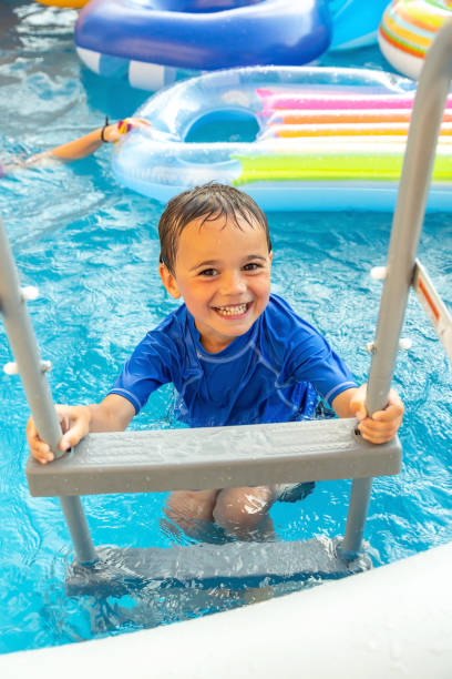 istock Young Boy Climbing Swimming Pool Ladder 1323921316