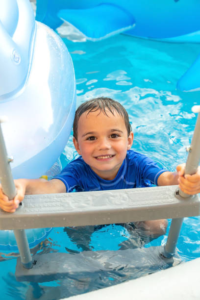 istock Young Boy Climbing Swimming Pool Ladder 1323921349