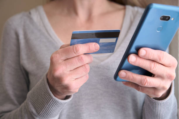 istock Online shopping concept. Female holding credit card while using her smart phone for inputting card information and making payment. Lifestyle and technology. Close up. 1323922396