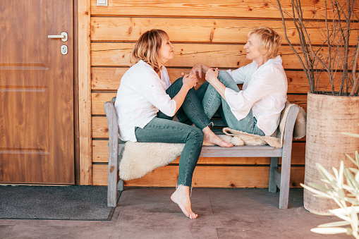 Portrait of two women on wooden background sitting opposite each other spending free time together