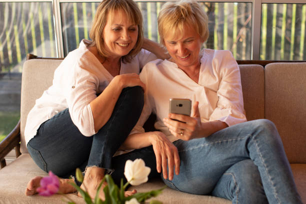 istock Two 55 years old ladies having fun using mobile device, female friendship concept 1323923890