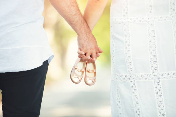 future parents holding a pair of unborn baby's little shoes - pair couple mid adult happiness imagens e fotografias de stock